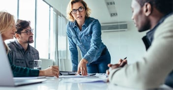 Team leader pointing at materials on conference table