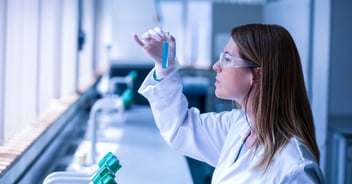 Scientist at bench, closely examining test tube