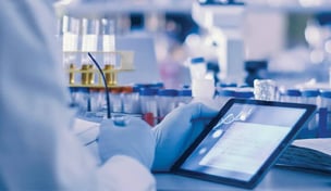 Photo of scientist holding computer tablet at bench