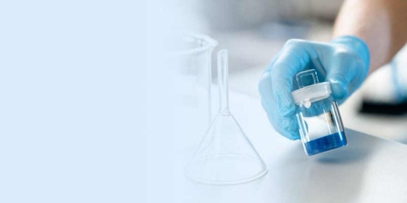 Close-up of gloved hand with beaker