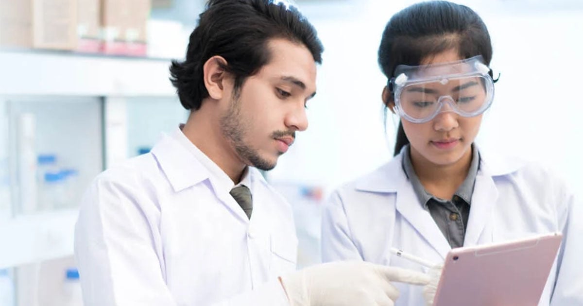 two scientists in lab consulting data on tablet